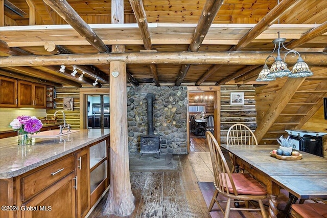 kitchen featuring a wood stove, wood ceiling, light stone countertops, dark wood-type flooring, and beam ceiling