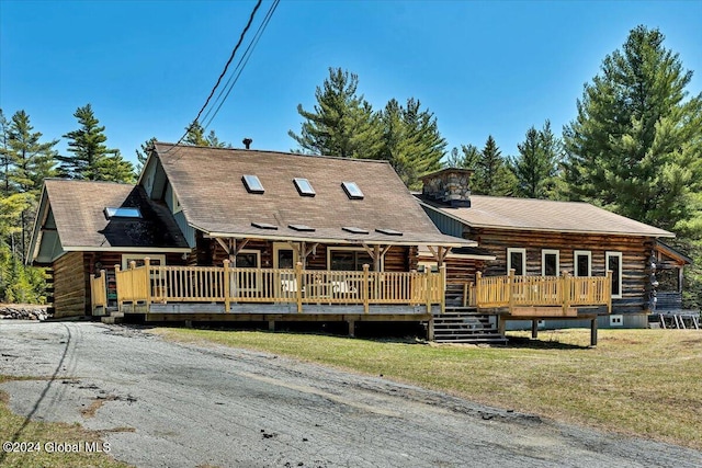 log cabin with a wooden deck and a front yard