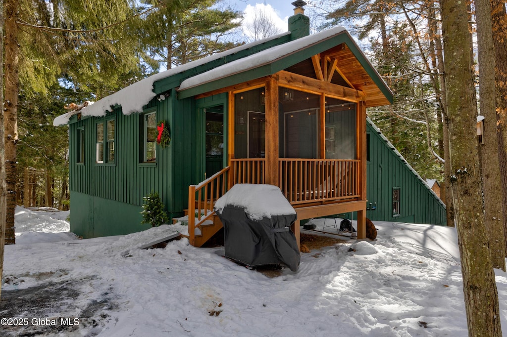 snow covered house featuring a sunroom