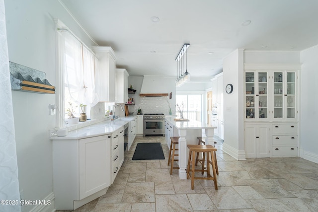 kitchen featuring a center island, open shelves, high end stainless steel range, white cabinets, and a sink