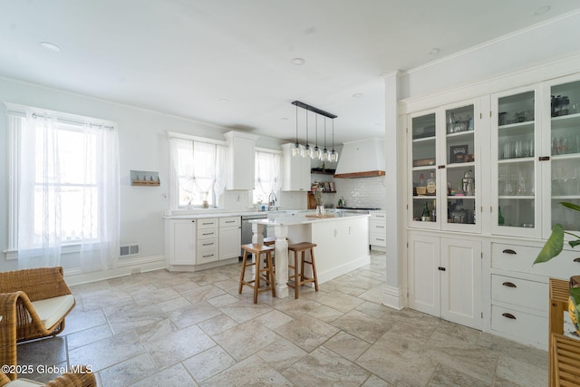 kitchen featuring visible vents, dishwasher, a kitchen breakfast bar, custom exhaust hood, and light countertops