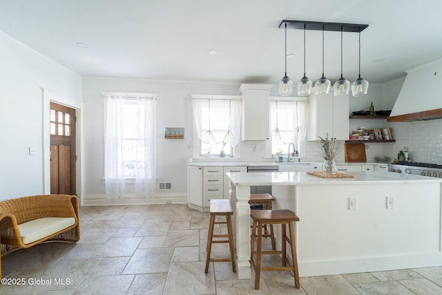 kitchen featuring a center island, white cabinetry, backsplash, and stone tile floors