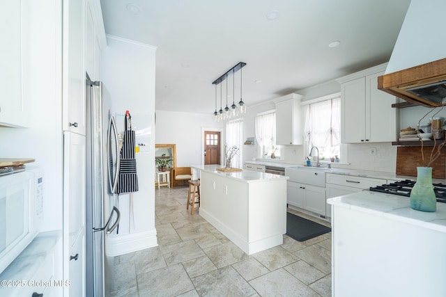 kitchen featuring appliances with stainless steel finishes, a center island, premium range hood, white cabinetry, and a sink