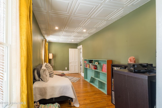 bedroom with light wood finished floors, an ornate ceiling, and baseboards