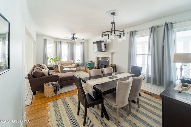 dining room with an inviting chandelier, a fireplace, and wood finished floors