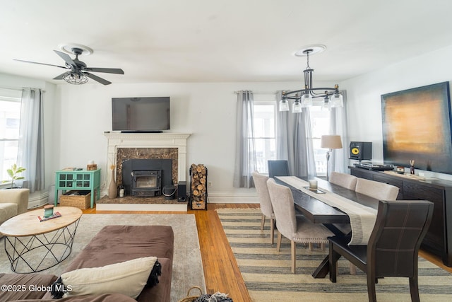 dining room featuring ceiling fan with notable chandelier, wood finished floors, and baseboards