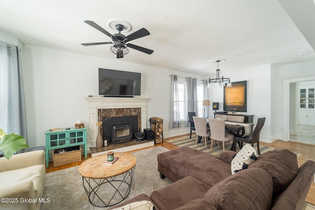 living room with ceiling fan with notable chandelier, wood finished floors, and baseboards