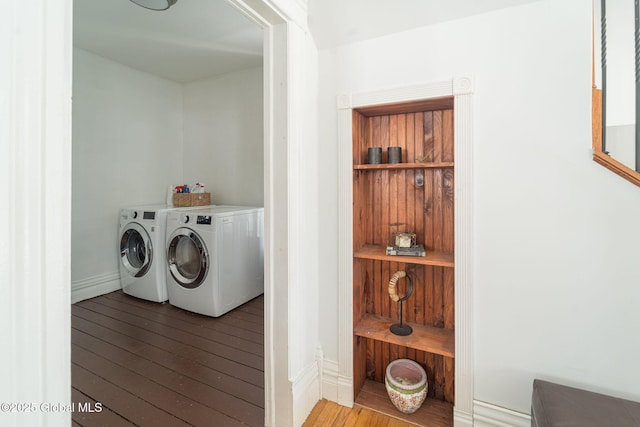 washroom featuring laundry area, baseboards, separate washer and dryer, and hardwood / wood-style flooring