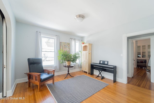 living area featuring arched walkways, wood finished floors, and baseboards