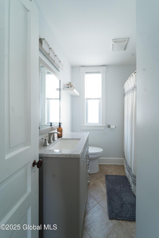 full bath with toilet, tile patterned floors, baseboards, and vanity