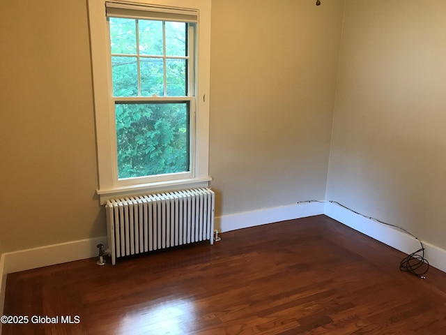 empty room featuring wood-type flooring and radiator