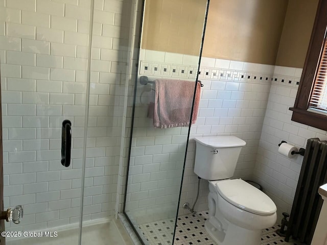 bathroom featuring a shower with shower door, radiator, tile walls, and toilet