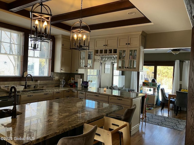 kitchen featuring a healthy amount of sunlight, a breakfast bar, hanging light fixtures, and dark stone counters