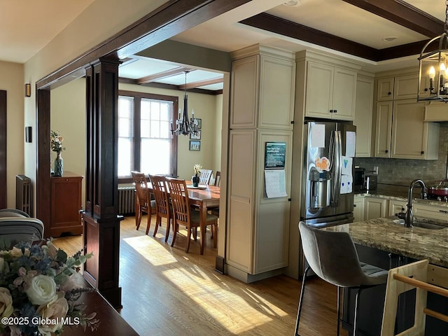 kitchen with sink, hanging light fixtures, light stone counters, a notable chandelier, and cream cabinetry