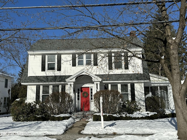 view of front facade featuring a chimney and a shingled roof