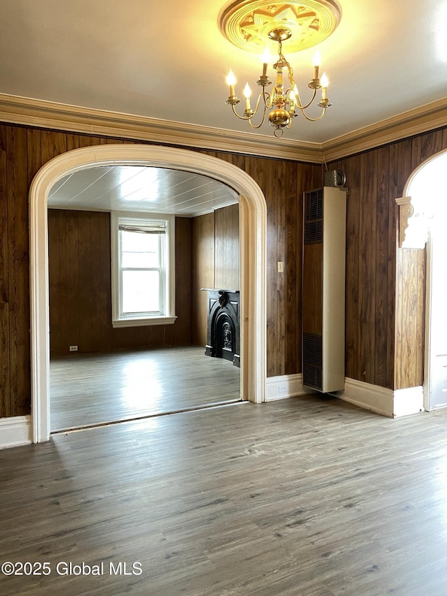 interior space with wood-type flooring, ornamental molding, a notable chandelier, and wood walls