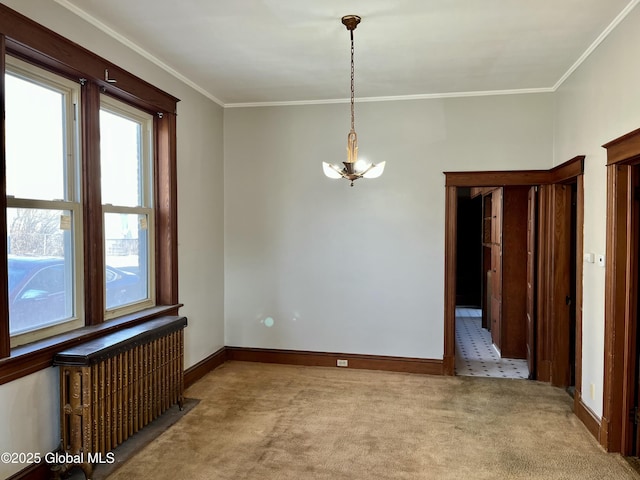 carpeted spare room with crown molding, radiator heating unit, and a chandelier