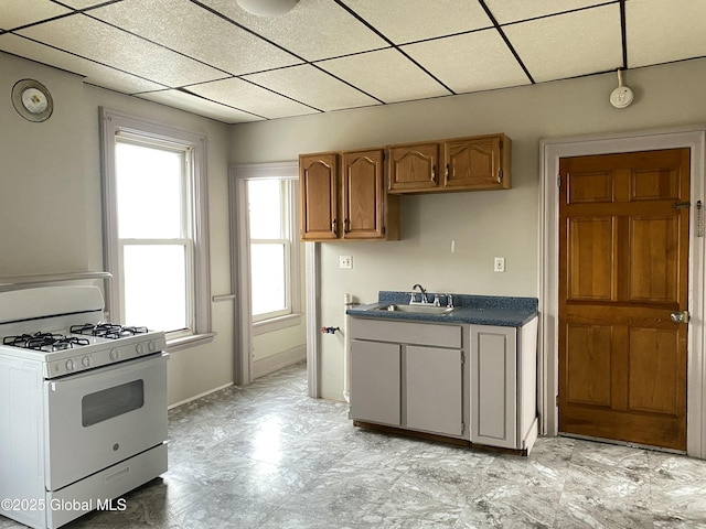 kitchen featuring a paneled ceiling, white gas range, and sink