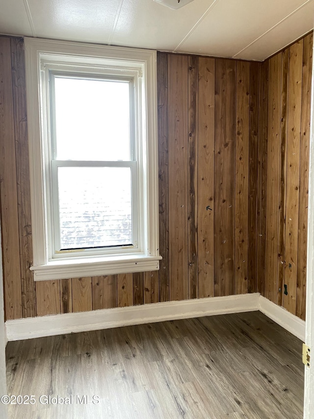 empty room featuring hardwood / wood-style flooring and wooden walls