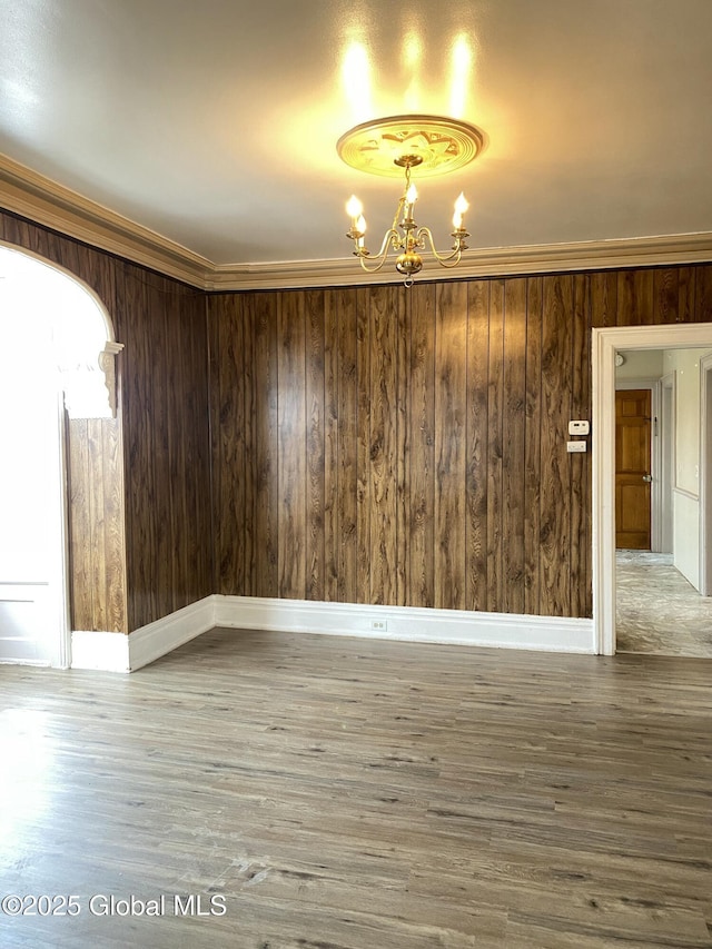 unfurnished room featuring ornamental molding, wood-type flooring, and an inviting chandelier