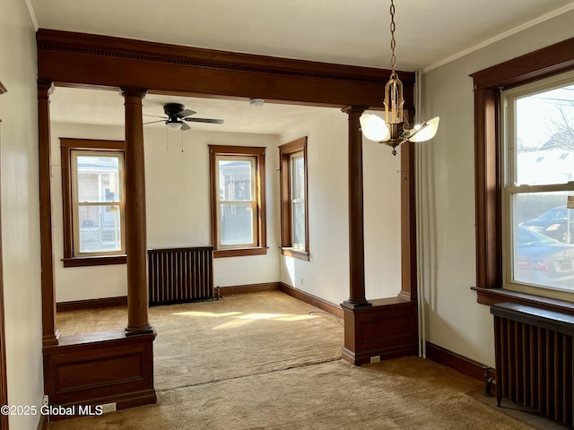 carpeted empty room featuring radiator, crown molding, decorative columns, and ceiling fan