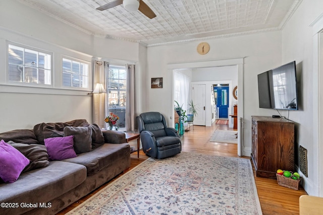 living room featuring crown molding, ceiling fan, and light hardwood / wood-style floors