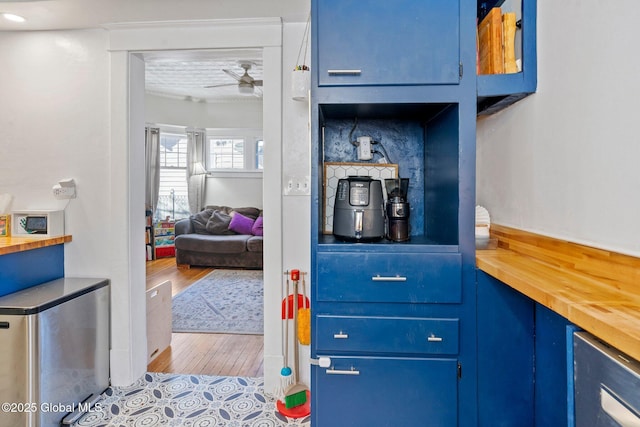 interior space featuring blue cabinetry, ceiling fan, light hardwood / wood-style floors, and stainless steel refrigerator