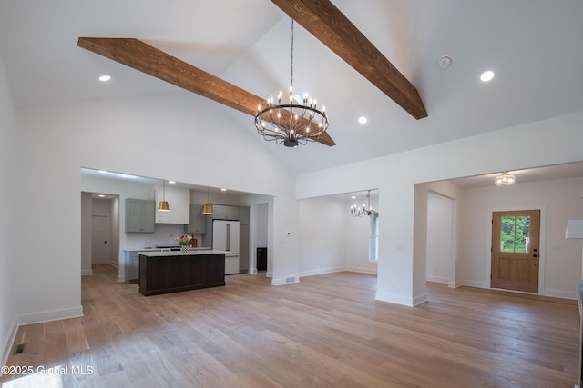 unfurnished living room with beamed ceiling, light wood-type flooring, and a chandelier