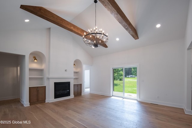 unfurnished living room featuring an inviting chandelier, high vaulted ceiling, hardwood / wood-style floors, and beam ceiling