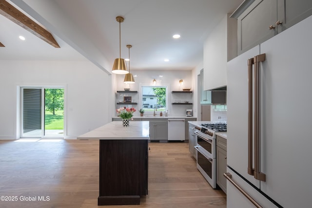 kitchen with pendant lighting, light hardwood / wood-style flooring, a center island, high end appliances, and light stone countertops