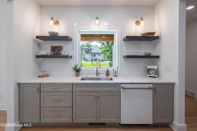 bar with sink, gray cabinetry, wood-type flooring, dishwasher, and light stone countertops