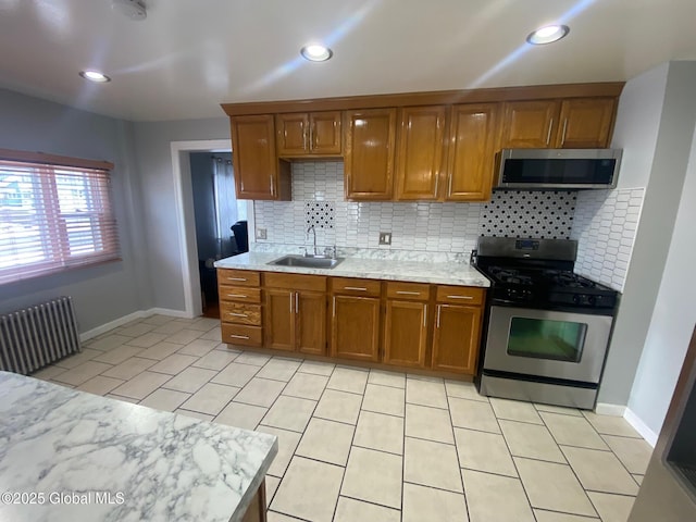 kitchen featuring sink, radiator heating unit, stainless steel appliances, tasteful backsplash, and light tile patterned flooring