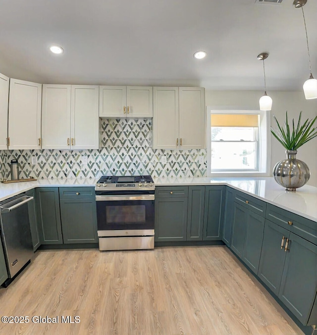 kitchen featuring decorative light fixtures, light hardwood / wood-style flooring, white cabinets, and appliances with stainless steel finishes