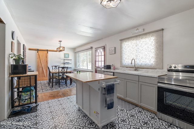 kitchen featuring pendant lighting, sink, a center island, electric range, and a barn door