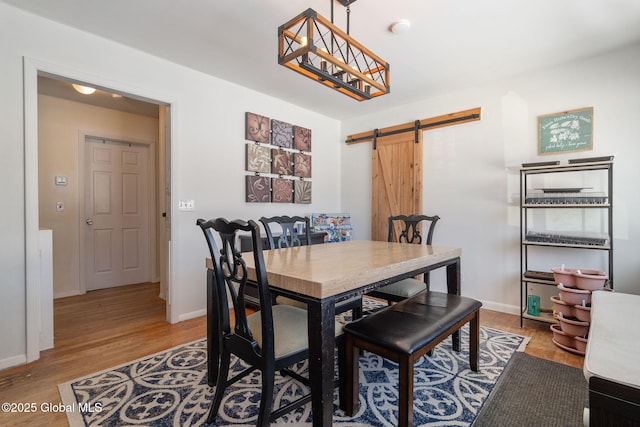 dining room with light hardwood / wood-style flooring and a barn door