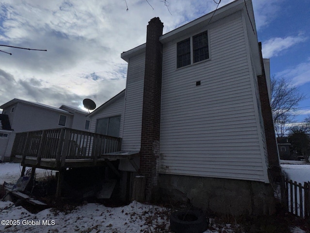 snow covered house with a wooden deck