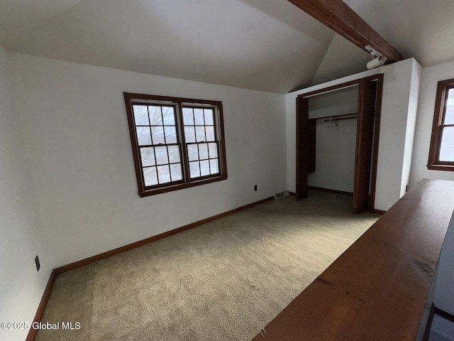 unfurnished bedroom featuring vaulted ceiling with beams, light colored carpet, and a closet