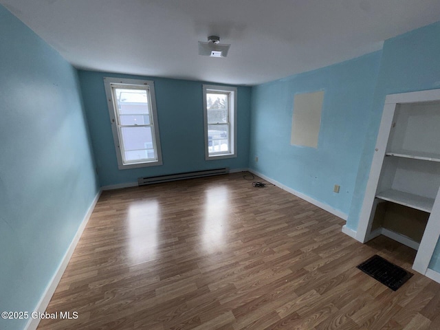 unfurnished room with dark hardwood / wood-style floors and baseboard heating