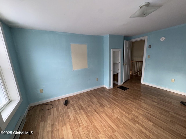 empty room with light hardwood / wood-style floors and baseboard heating