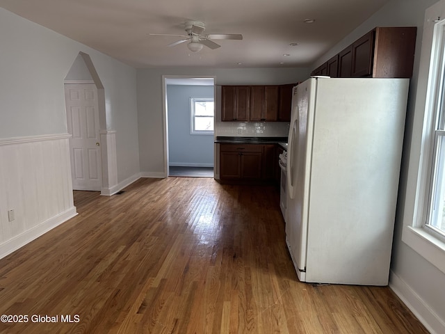 kitchen featuring dark brown cabinetry, white refrigerator, hardwood / wood-style flooring, ceiling fan, and decorative backsplash