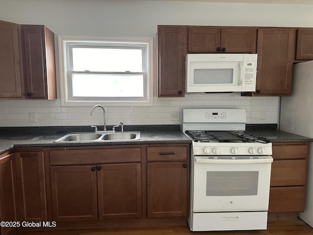 kitchen featuring white appliances, sink, and backsplash