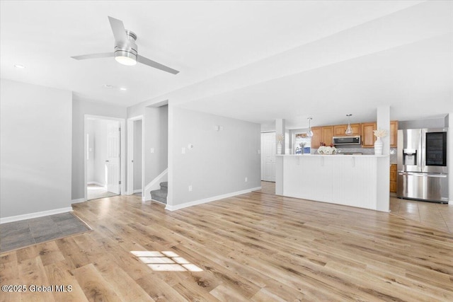 unfurnished living room featuring ceiling fan and light hardwood / wood-style floors