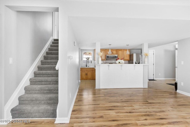 kitchen with decorative light fixtures, light wood-type flooring, and appliances with stainless steel finishes