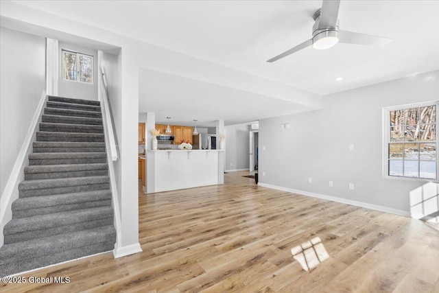 unfurnished living room featuring ceiling fan and light wood-type flooring