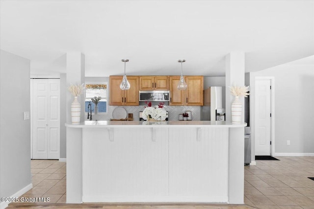 kitchen with appliances with stainless steel finishes, pendant lighting, a kitchen breakfast bar, decorative backsplash, and light tile patterned floors