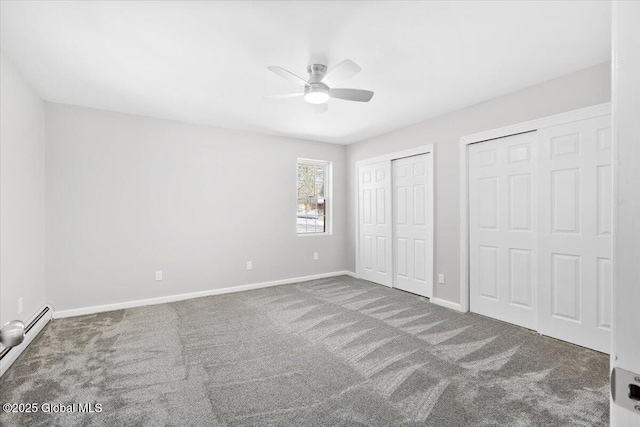 unfurnished bedroom with a baseboard radiator, carpet, two closets, and ceiling fan