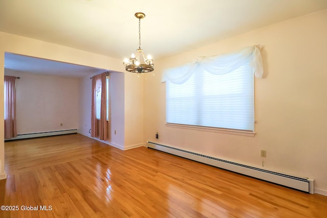 empty room featuring hardwood / wood-style flooring, a baseboard radiator, and a notable chandelier