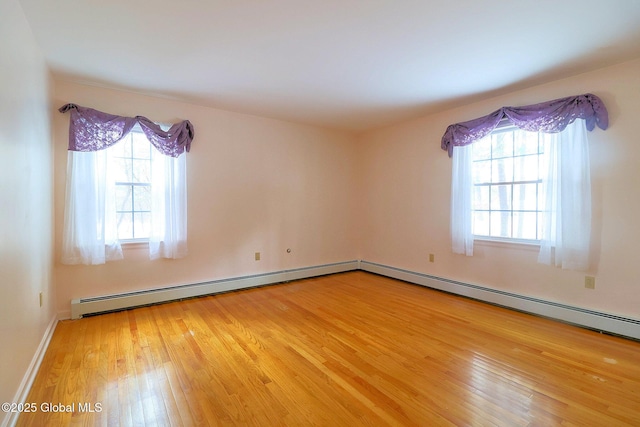 unfurnished room with a wealth of natural light, wood-type flooring, and a baseboard radiator