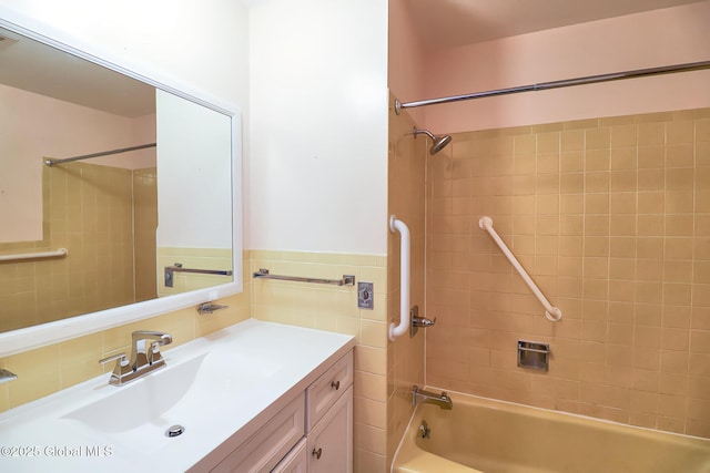 bathroom with tile walls, vanity, and tiled shower / bath