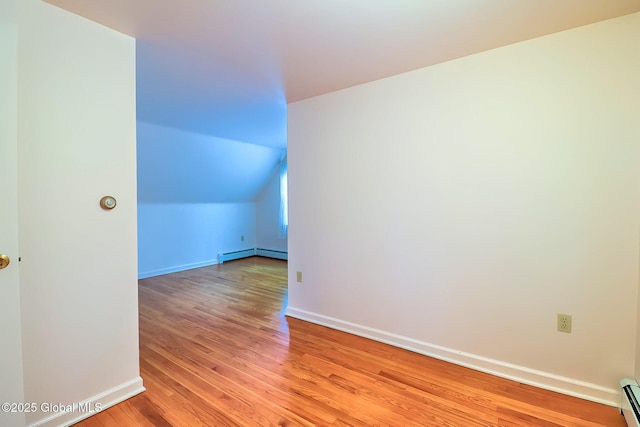 additional living space featuring baseboard heating, lofted ceiling, and light hardwood / wood-style flooring